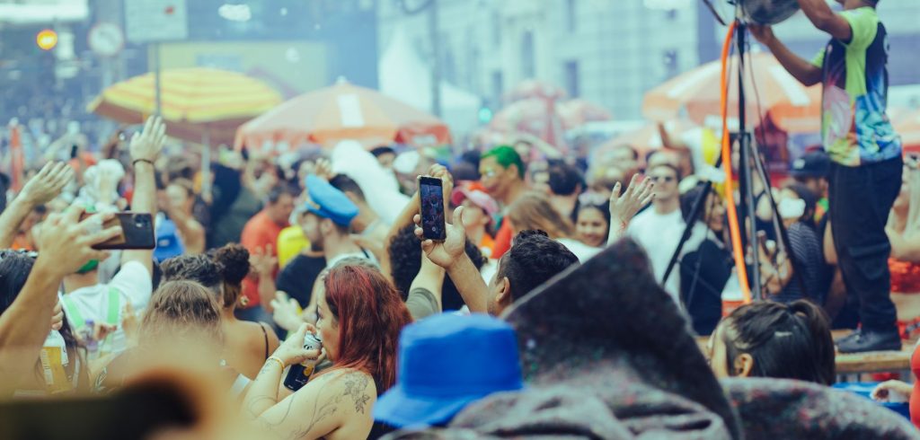 A lively street festival with a diverse crowd enjoying music and festivities outdoors. — Coronavirus disease 2019