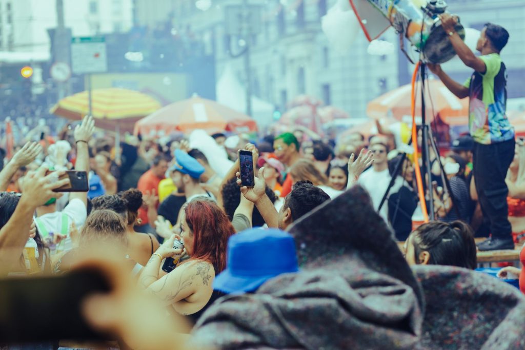 A lively street festival with a diverse crowd enjoying music and festivities outdoors. — Coronavirus disease 2019