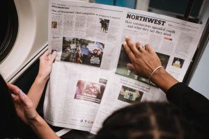 People reading a newspaper on a subway train, highlighting current events and diverse perspectives. — Der Einfluss der Lizenz