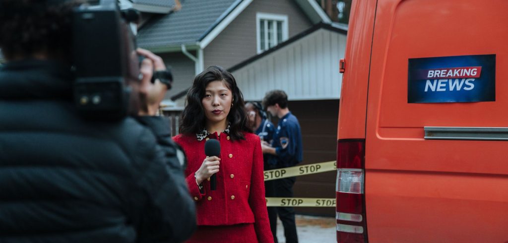 Female reporter in red with microphone reporting live at an outdoor crime scene with a news van. — Die beliebtesten Tischspie