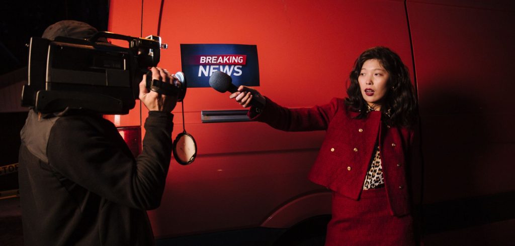 Asian female reporter with cameraman conducting a nighttime news broadcast beside a news van. — Die besten Live-Casino-Erlebn