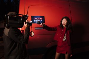 Asian female reporter with cameraman conducting a nighttime news broadcast beside a news van. — Die besten Live-Casino-Erlebn