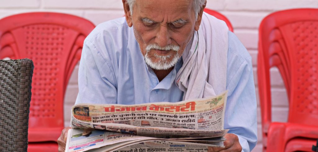 Elderly man engaging in daily reading of a newspaper while seated outdoors. — Ein umfassender Leitfaden zur Auszahlung bei Ro