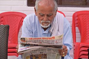 Elderly man engaging in daily reading of a newspaper while seated outdoors. — Ein umfassender Leitfaden zur Auszahlung bei Ro