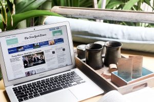 High angle of modern laptop with news on screen placed on table next to tin cups — Goldwin Casino: Wie stehen die Auszahlungs
