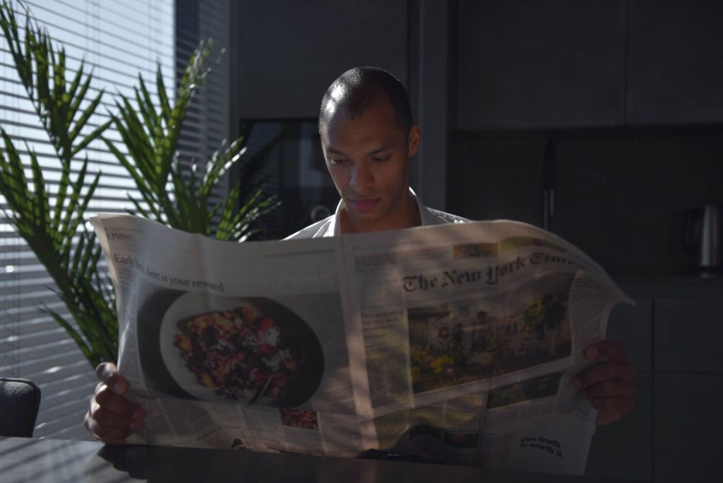 Businessman focused on reading newspaper in a sunny indoor office setting. — Gransino Casino : La Puissance Ultime pour Sessi