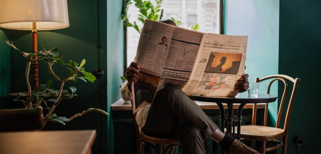 A man sits in a cozy café corner, enjoying a newspaper and relaxed ambiance. — Sind die Jackpot-Spiele im Turbo Winz Casino l