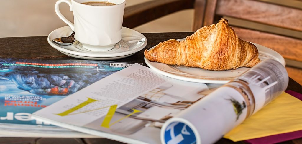 Enjoy a peaceful morning with coffee, croissant, and reading material on a wooden table. — test123123