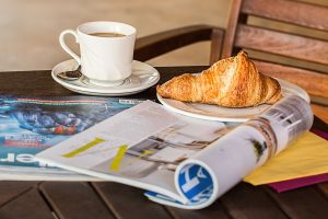 Enjoy a peaceful morning with coffee, croissant, and reading material on a wooden table. — test123123