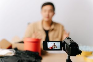 A blogger sits in front of a camera for filming a video indoors. — The Founding of YouTube A Short History