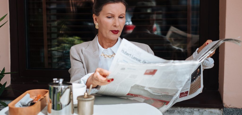 Sophisticated woman enjoying her morning newspaper at a cozy outdoor cafe. — Wonderluck Casino in 2023: Neue Funktionen im Te